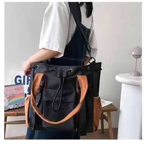 Detailed view of a contrast-color tote bag with drawstring closure and wide shoulder strap