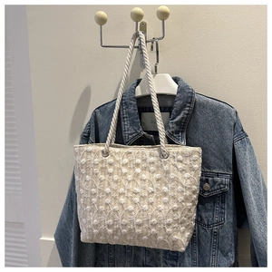 Close-up of cream woven tote bag with white daisy embroidery and rope handles