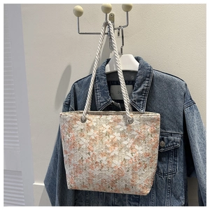 Detailed close-up of a floral canvas tote bag with rustic white rope handles and metal eyelets