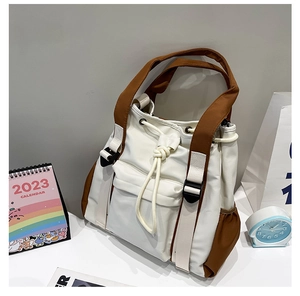 Detail of a large-capacity contrast tote bag with drawstring closure and front pocket flaps