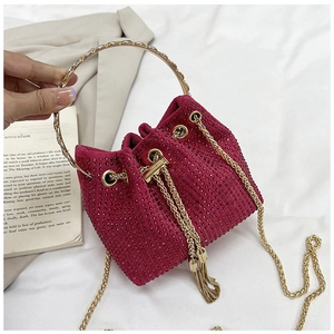 Detail of fuchsia rhinestone bucket bag with gold handle and chain fringe strap