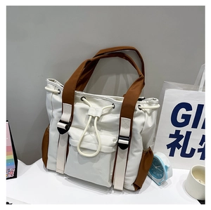 Detail of color-block tote bag with drawstring, flap pocket, and brown shoulder straps