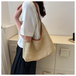Detailed view of the woven hollow pattern on a summer straw tote bag with brown leather strap
