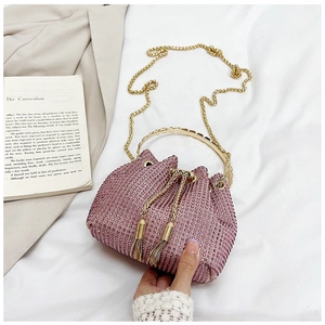 Detail of pink rhinestone bucket bag featuring gold metal ring handles and drawstring tassels