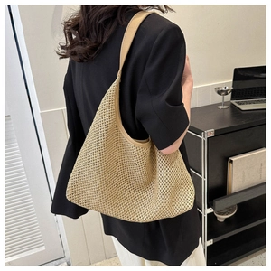 Dettaglio di una borsa tote in paglia beige con trama a rete e ampia tracolla in pelle