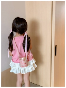 Vue arrière d'un enfant portant un petit sac seau rose à imprimé cerise et doré