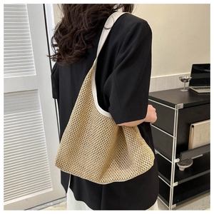 Detail der gewebten Strohtasche mit weißen Lederriemen an der Schulter des Models