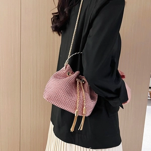 Elegant pink rhinestone drawstring bucket bag with gold chain strap worn by a model