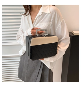 Detail showing the two-tone quilted leather bag with silver metal handle held by a model