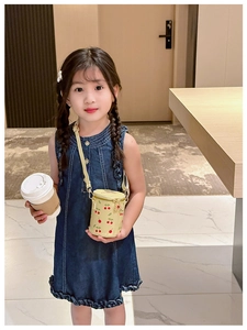 Détail d'un sac seau jaune à imprimé cerise et d'une robe en jean bleu pour filles