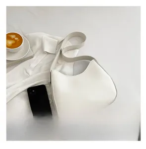 Witte minimalistische hobo-tas naast een smartphone voor maatvergelijking