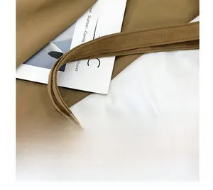 Close-up of reinforced canvas tote handles with premium stitching and brown fabric texture