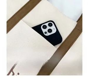 Close-up of canvas tote bag with functional front pocket for smartphone storage