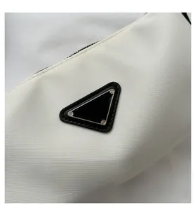 Detailed close-up of the white nylon fabric texture and triangular metal logo plate