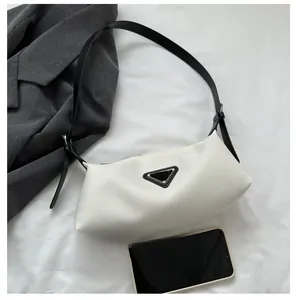 Detail view of white underarm bag with black logo and smartphone for size reference