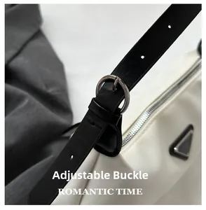 Close-up of adjustable leather strap buckle and metal logo on white nylon handbag