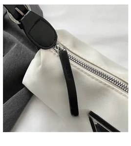 Close-up of smooth silver zipper and triangle logo on white nylon underarm bag