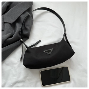Detail view of black nylon hobo bag with adjustable leather strap and metal triangle logo