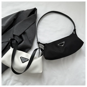Detail of minimalist underarm bags in black and cream featuring triangular metal logo accents