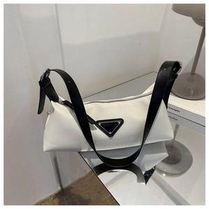 Detail showing the white fabric texture and black leather strap of the underarm bag
