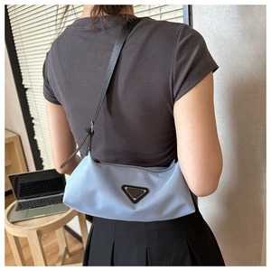 Detail of light blue nylon crescent bag showing logo patch and shoulder strap style