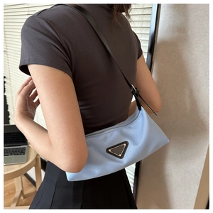 Detail of light blue nylon underarm bag with black leather strap and triangular patch