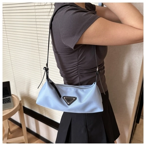 Side view of a light blue nylon hobo bag with iconic triangle logo and black strap
