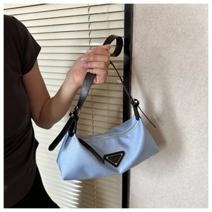 Detail of light blue nylon underarm bag featuring silver zipper and adjustable strap