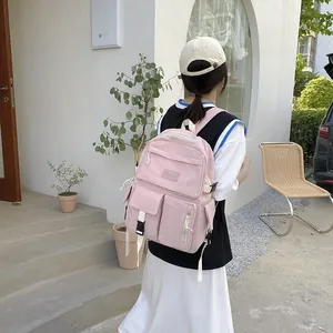 Pink multi-pocket school backpack shown on a model with white architectural background