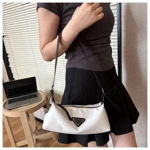 Detail view of white nylon shoulder bag with black strap and iconic triangle logo badge