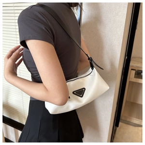 Detail view of the white minimalist underarm bag with black triangle metal plaque and strap