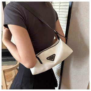 Minimalist white nylon shoulder bag with black leather strap worn by a model in daily life
