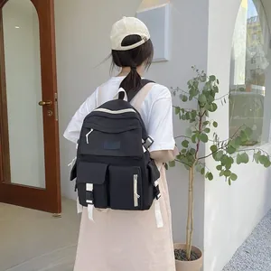 Rear view of a black multi-pocket backpack with white zipper details on a model