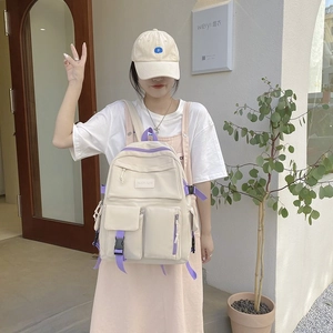 Detail of cream canvas backpack with purple zippers and buckle pocket on model