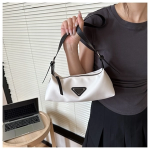 Detailed view of white minimalist underarm bag with black triangle plaque and leather strap