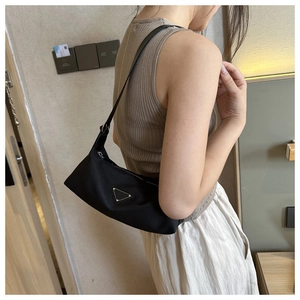 Close-up of a black nylon underarm bag featuring a metallic triangular logo and silver zipper
