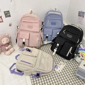 Detailed view of large capacity nylon school backpacks in pink, blue, black and beige