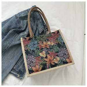 Close-up of retro floral embroidery tote bag with woven handles on white fabric