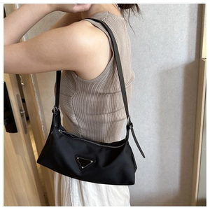 Detailed side view of black nylon underarm bag with silver zipper and leather strap