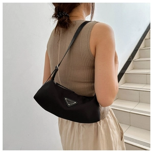 Detailed view of the black nylon crescent bag with an iconic metallic triangular logo plaque