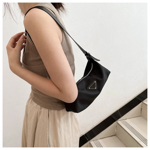 Detail showing smooth nylon fabric and metal triangle logo on a black hobo underarm bag
