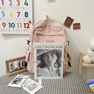 Close-up of pink minimalist student backpack featuring leather brand label and durable zippers