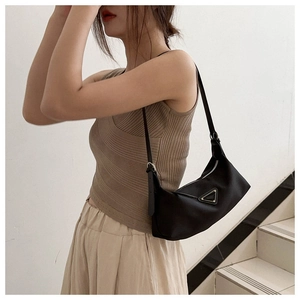 Detail of minimalist black nylon underarm bag with signature metal triangle logo