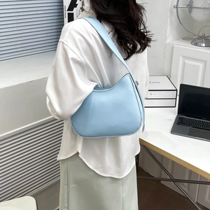 Lichtblauwe vintage hobo-emmer tas met brede riem, gedragen door model op kantoor