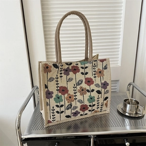 Retro jute tote bag with floral print and brown handles on a metal cart