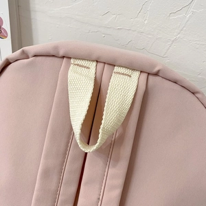 Detail view of pink backpack top handle showing durable stitching and canvas texture