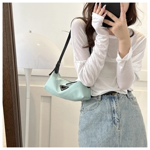 Mirror selfie showing mint green nylon hobo bag with black leather shoulder strap and logo