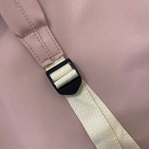 Detail view of adjustable plastic buckle and durable woven strap on pink casual backpack