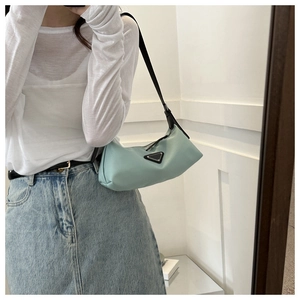 Detail view of mint green nylon hobo bag featuring a triangular plaque and black shoulder strap