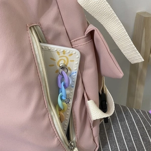 Detail view of pink canvas backpack side pocket with hidden zipper and colorful chain